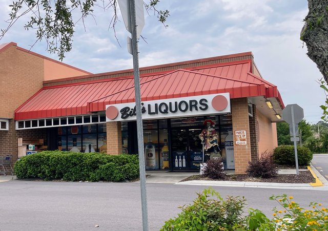 Bill's Liquors in Bluffton — red metal roof, the sign across the front and a pirate statue standing by the entrance