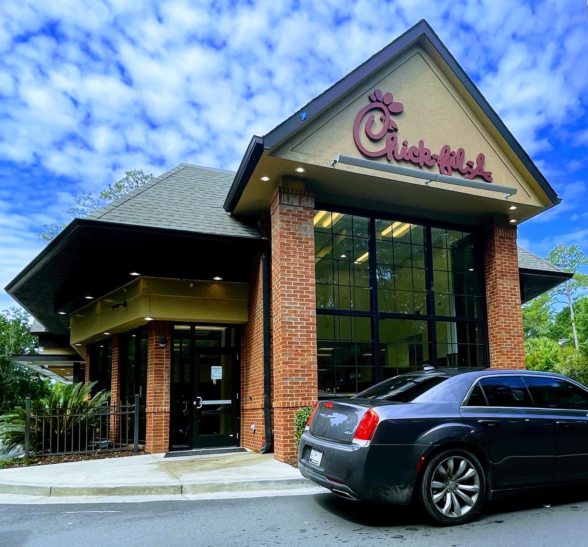 Chick-fil-A red script sign on a brick gable with a car in the drive-thru lane, Bluffton SC