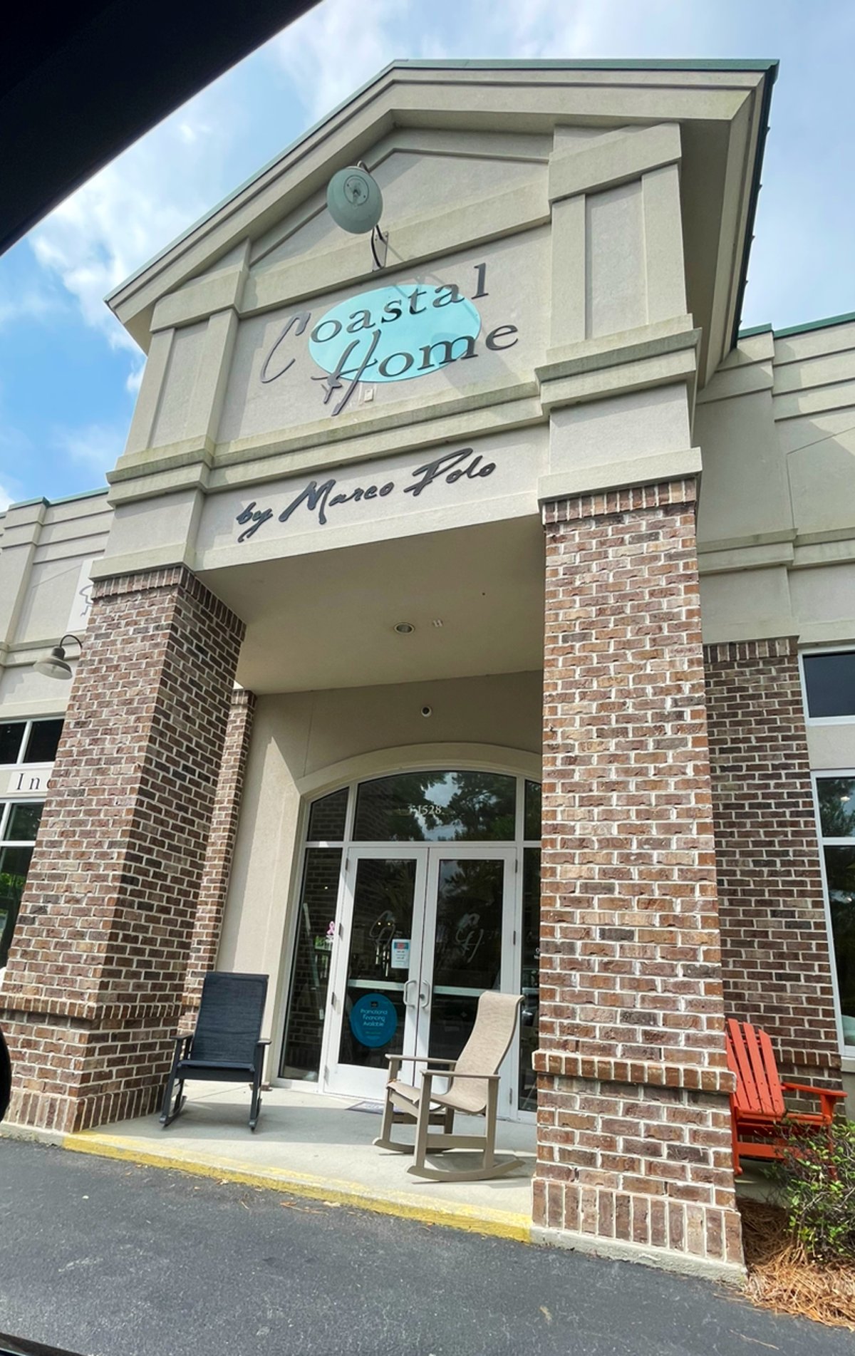 Coastal Home by Marco Polo storefront in Bluffton — brick pillars, rocking chairs on the porch, the aqua oval sign