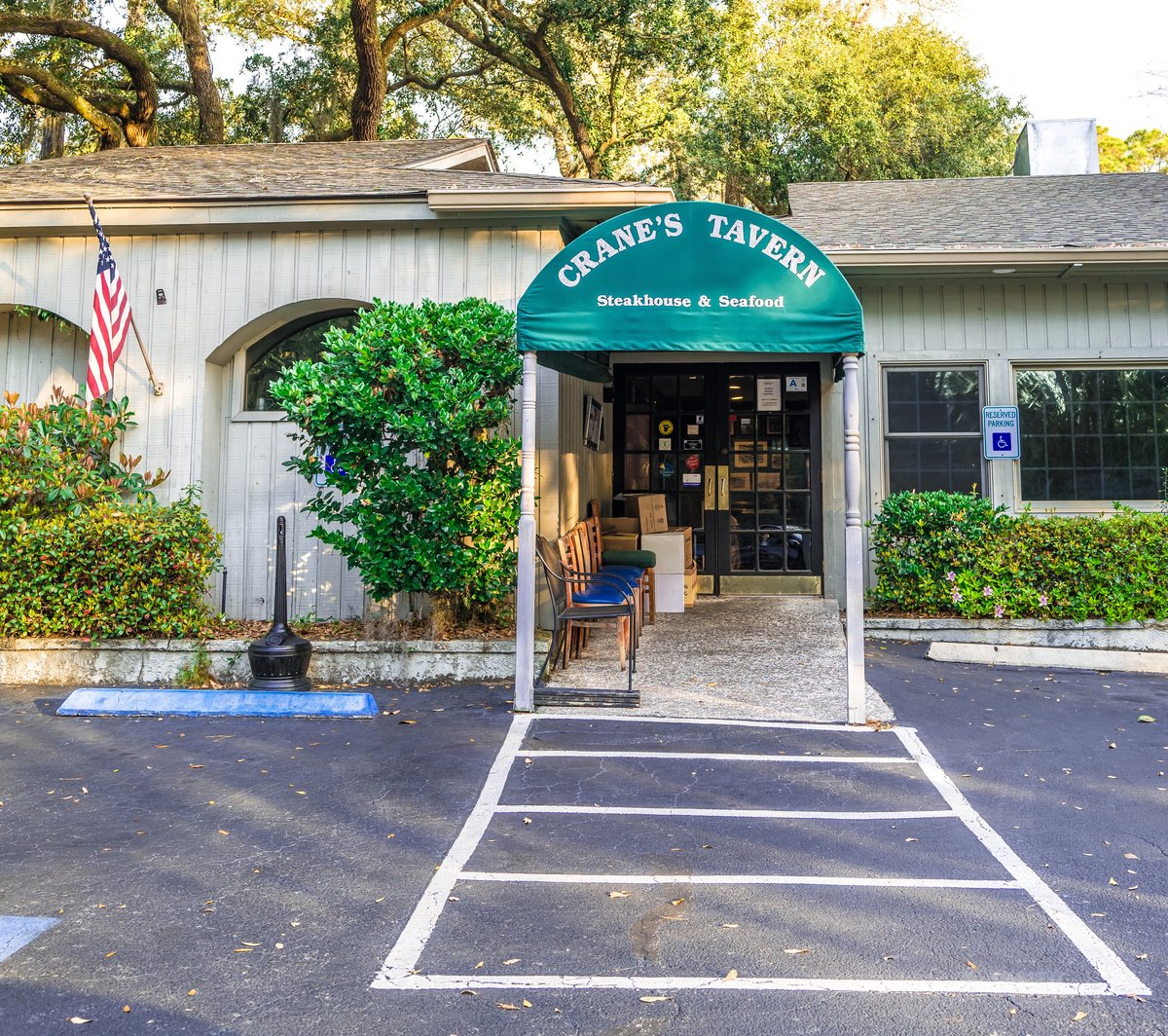 Crane's Tavern on Hilton Head Island — the green arched awning over the entrance, benches under it and a flag by the door