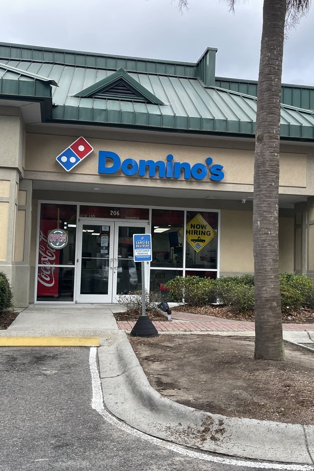 Domino's in Bluffton — the blue letters and domino tile over unit 206, a Now Hiring sign in the window