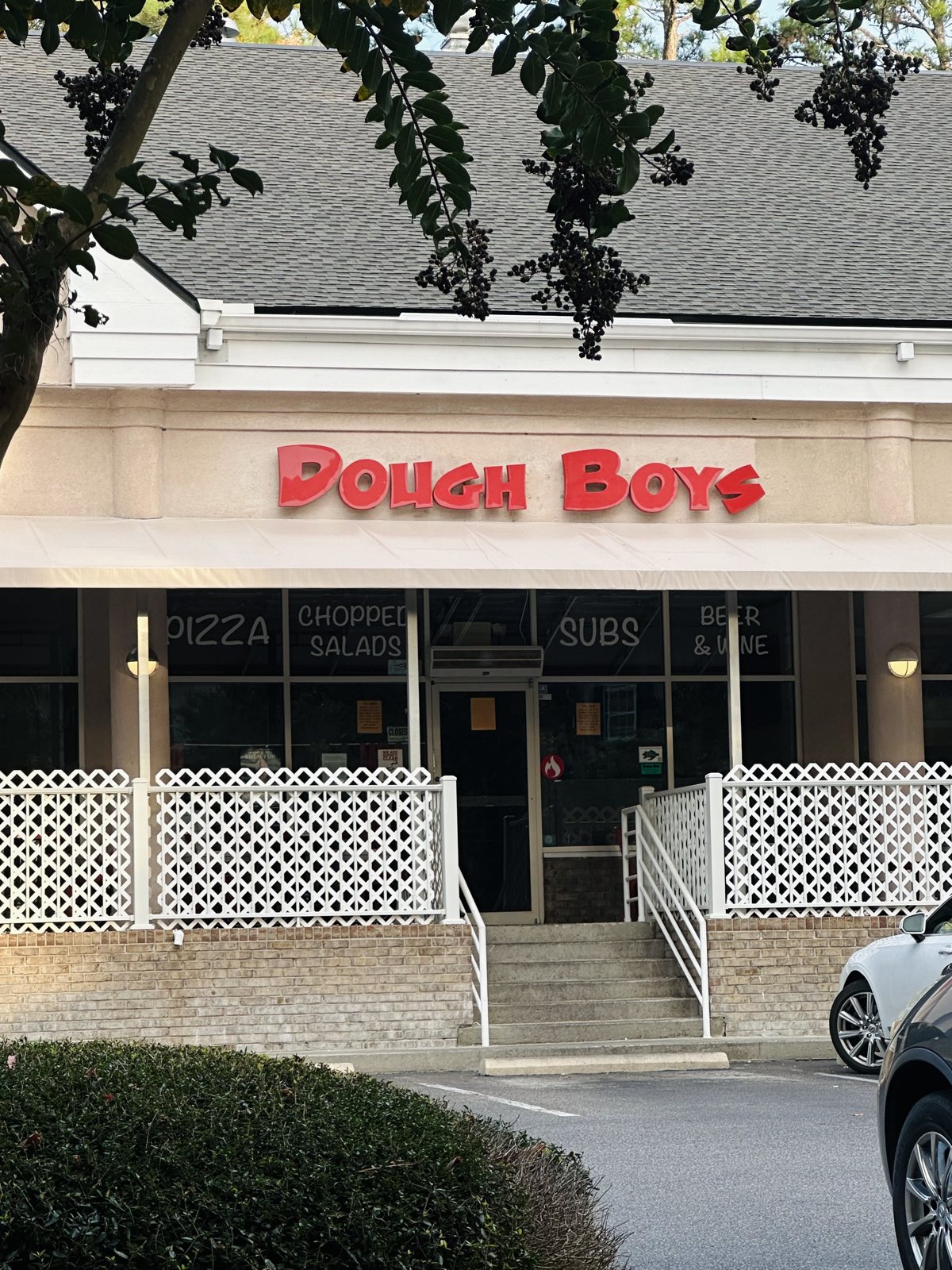 Dough Boys from the left — the sign and patio fence under the trees