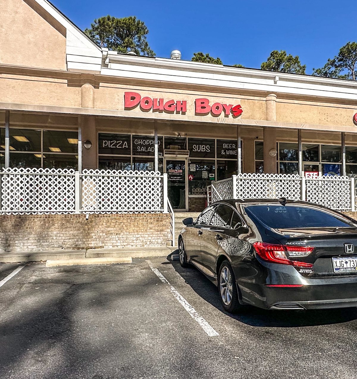 Dough Boys from the parking lot — the full storefront, red bubble letters, and the white lattice patio