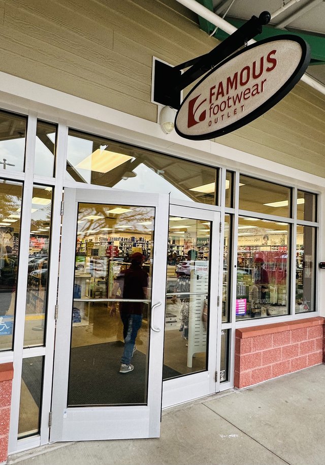 Famous Footwear Outlet at Tanger Outlets 1 in Bluffton — the oval blade sign over the glass doors, a shopper heading in