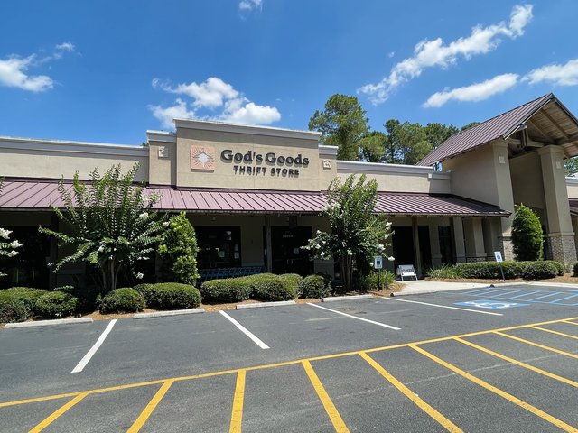 God's Goods Thrift Store in Bluffton — the sun logo and letters over a red metal awning, crape myrtles in bloom out front