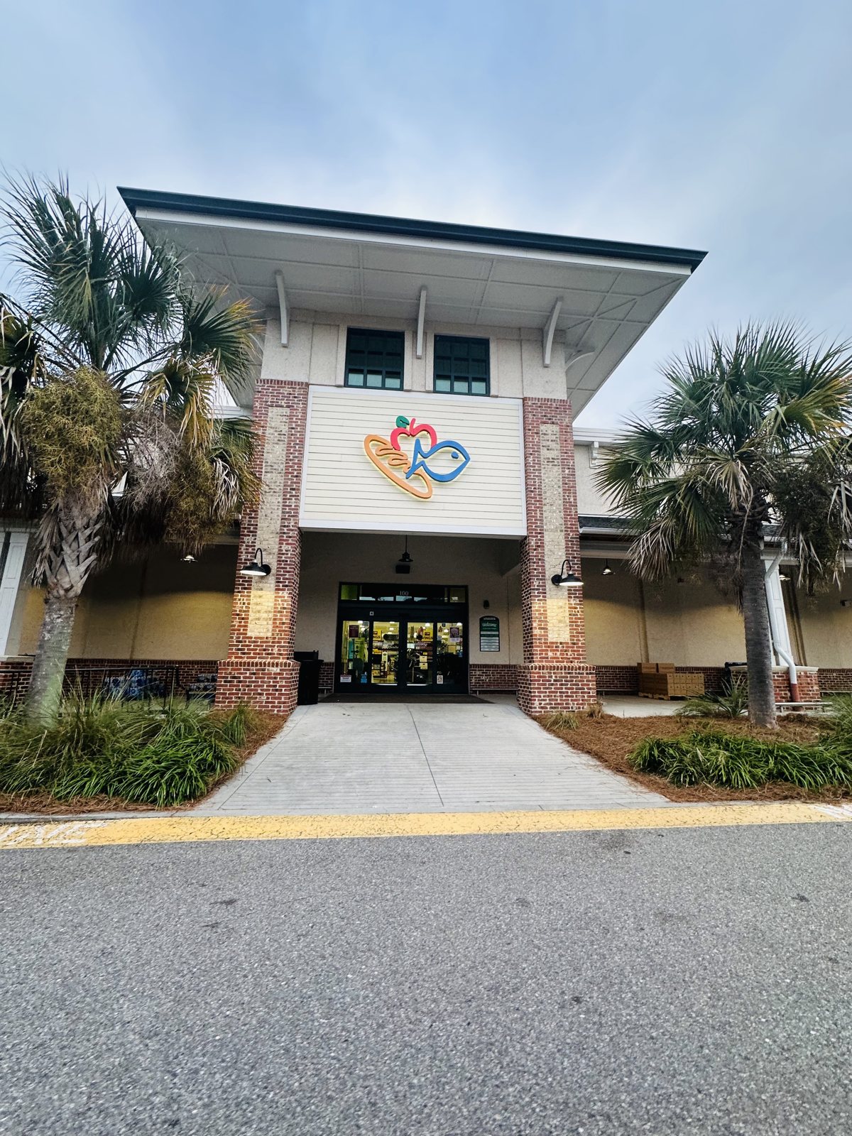 The Harris Teeter entrance — the market logo over the doors, between brick pillars and palmettos