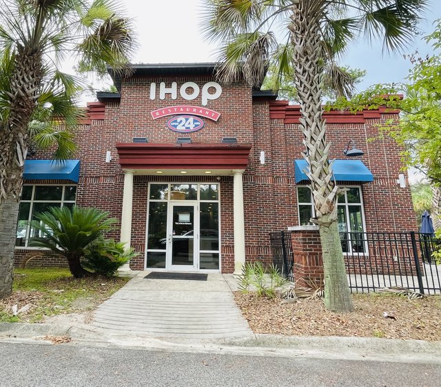 The Bluffton IHOP in Belfair Towne Village — white letters on brick, the 24-hour banner over the doors, palmettos framing the walk