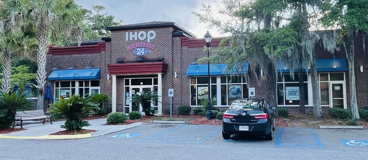 The IHOP in Belfair Towne Village from the parking lot — the whole brick building, palmettos, and blue awnings