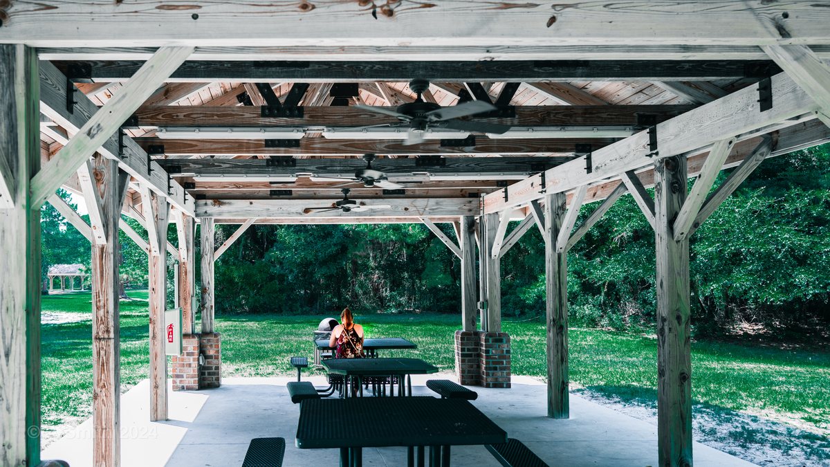 Under the pavilion. Inside the long picnic pavilion — timber posts, ceiling fans and tables for a crowd.