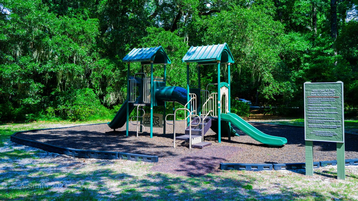 The playground. The main playground — slides, climbers and the rules sign — in the pines' shade.
