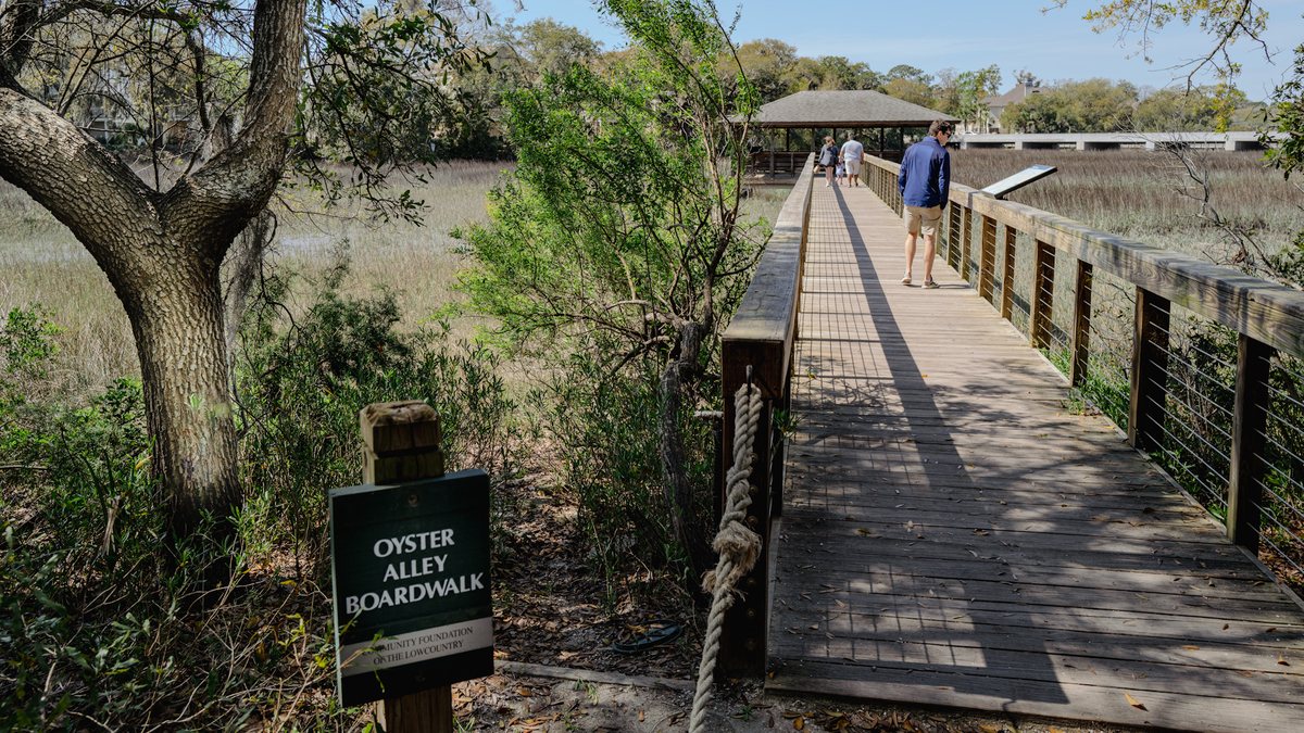 Oyster Alley. The boardwalk’s sign at the trail end, the creek beyond the rail.