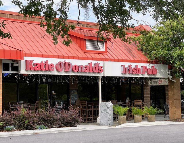 Katie O'Donald's Irish Pub in Bluffton — pink-red letters, patio tables under the red metal roof, a carved stone out front