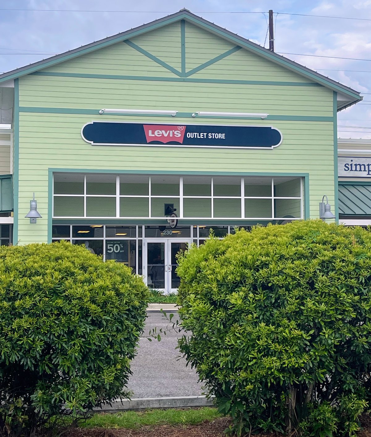Levi's Outlet Store at Tanger Outlets 1 in Bluffton — the batwing sign on a pale-green gabled building, hedges framing the walk in