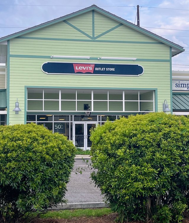 Levi's Outlet Store at Tanger Outlets 1 in Bluffton — the batwing sign on a pale-green gabled building, hedges framing the walk in