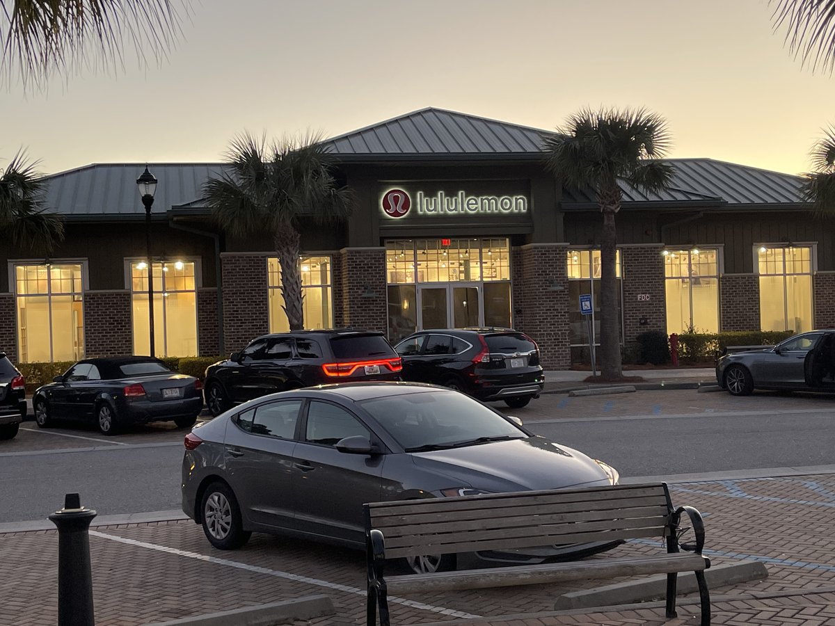 lululemon at Shelter Cove on Hilton Head Island at dusk — the lit red logo, brick front, palmettos and cars heading home