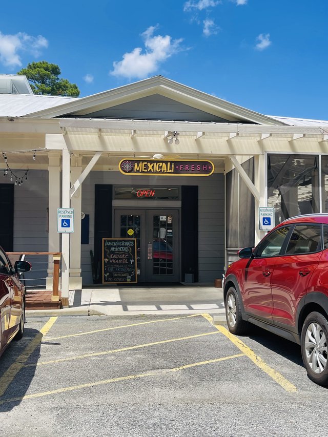 Mexicali Fresh entrance with yellow sign, pergola porch and neon OPEN sign, Bluffton SC