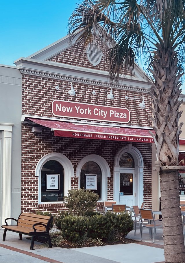 New York City Pizza in Bluffton — brick storefront with arched windows and a red awning