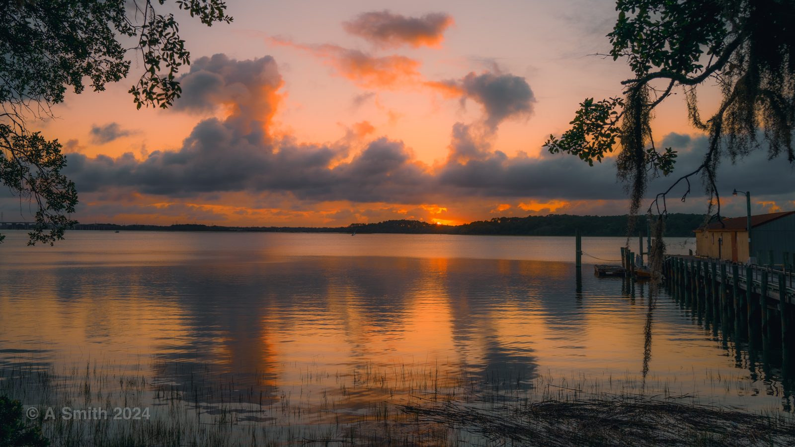 Sunset over Skull Creek from the dock on Pinckney Island's south shore, orange sky reflected in the water