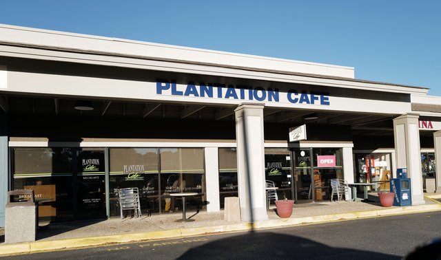 Plantation Cafe on Hilton Head Island — PLANTATION CAFE in blue letters over the walkway, patio tables and the OPEN sign in the door