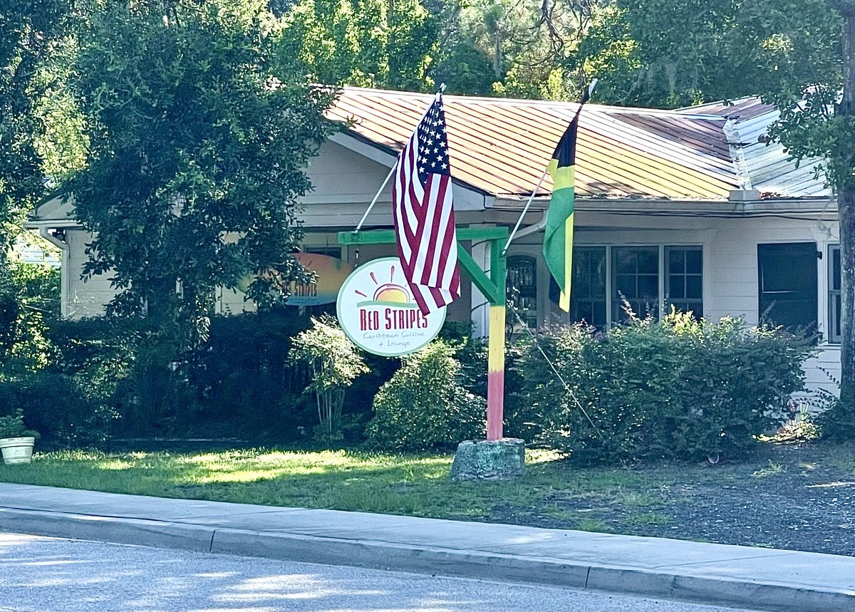 Red Stripes Caribbean restaurant round sign between American and Jamaican flags, May River Road, Bluffton SC