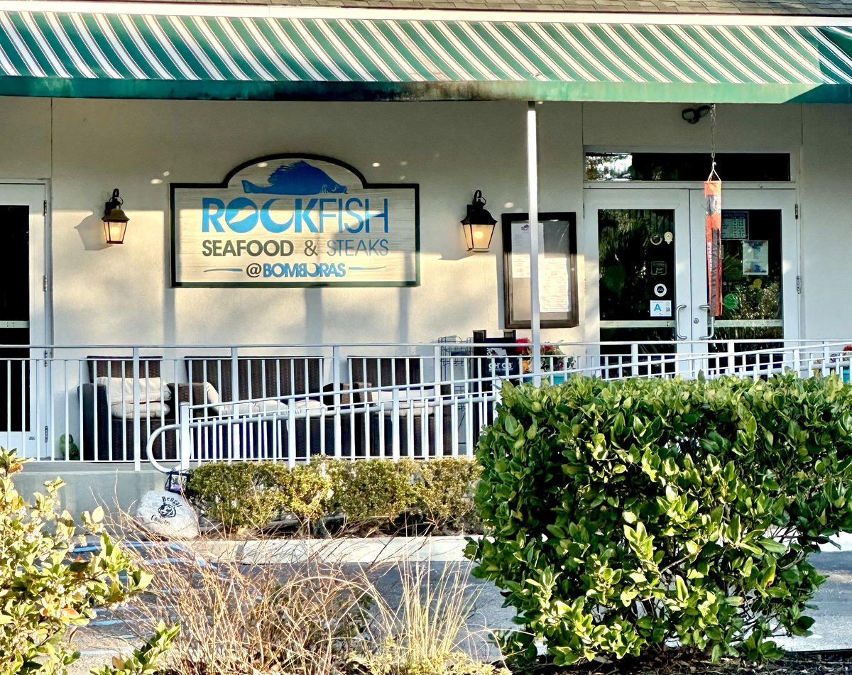 Rockfish Seafood & Steaks at Coligny — the fish sign reading ROCKFISH @ BOMBORAS under the striped awning, patio seating behind the rail