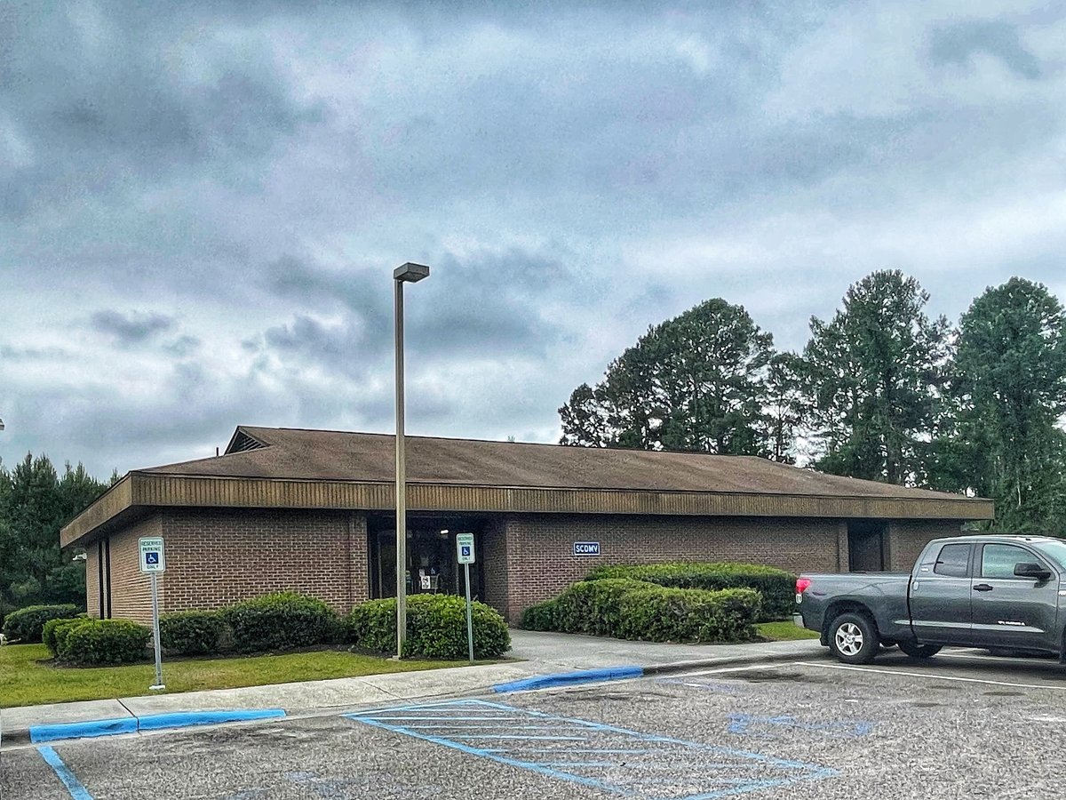The SCDMV office in Bluffton — a plain brick building under a grey sky, the little blue SCDMV sign on the wall