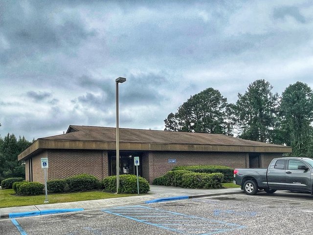 The SCDMV office in Bluffton — a plain brick building under a grey sky, the little blue SCDMV sign on the wall