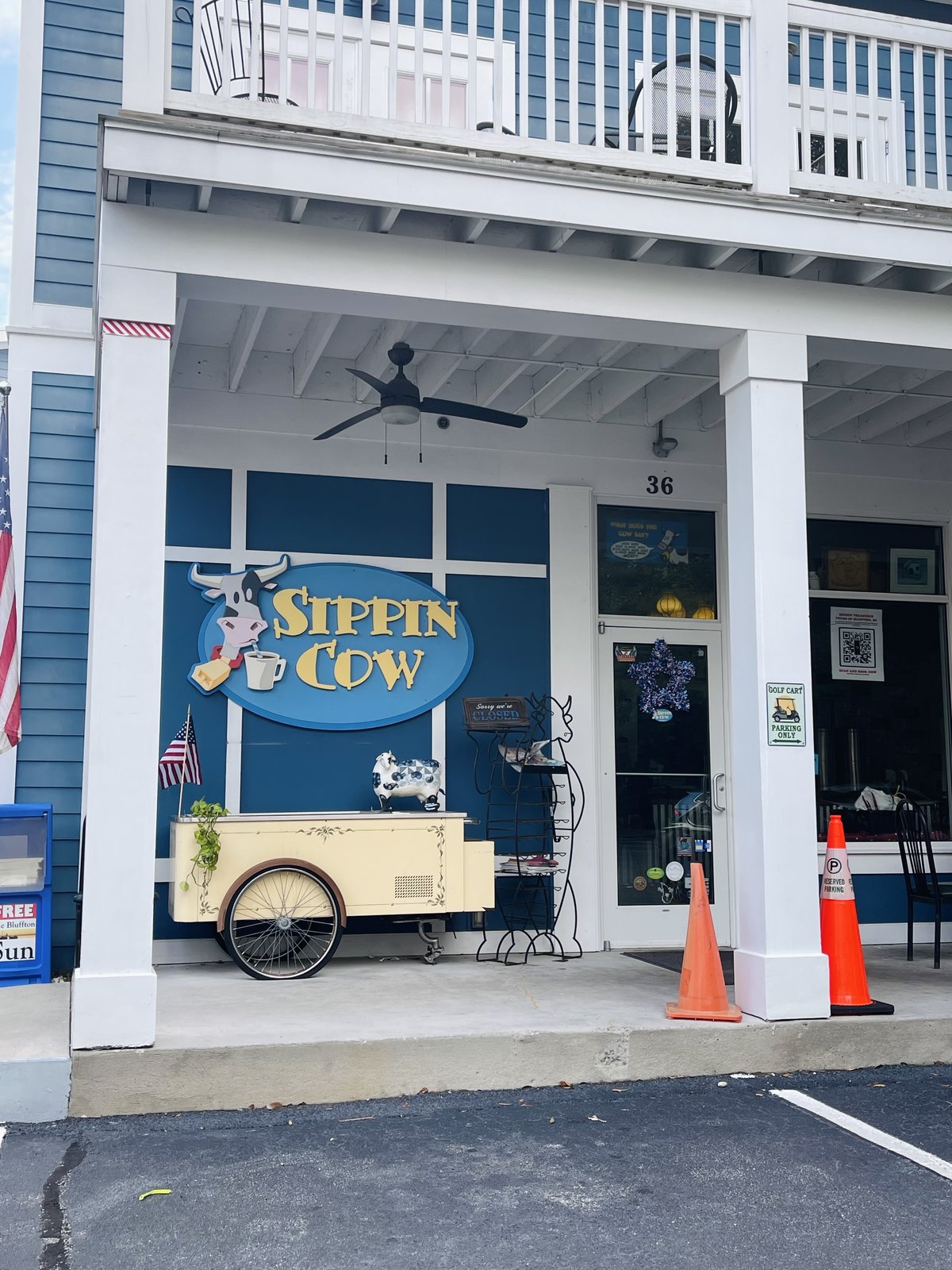 Sippin Cow in Bluffton — the cow sign with a coffee cup, an ice-cream cart on the columned porch and a spotted cow on top of it