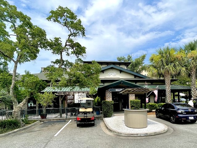 Skillets at Coligny Plaza — the cafe under green metal roofs, a golf cart parked at the rail and the host podium by the drive