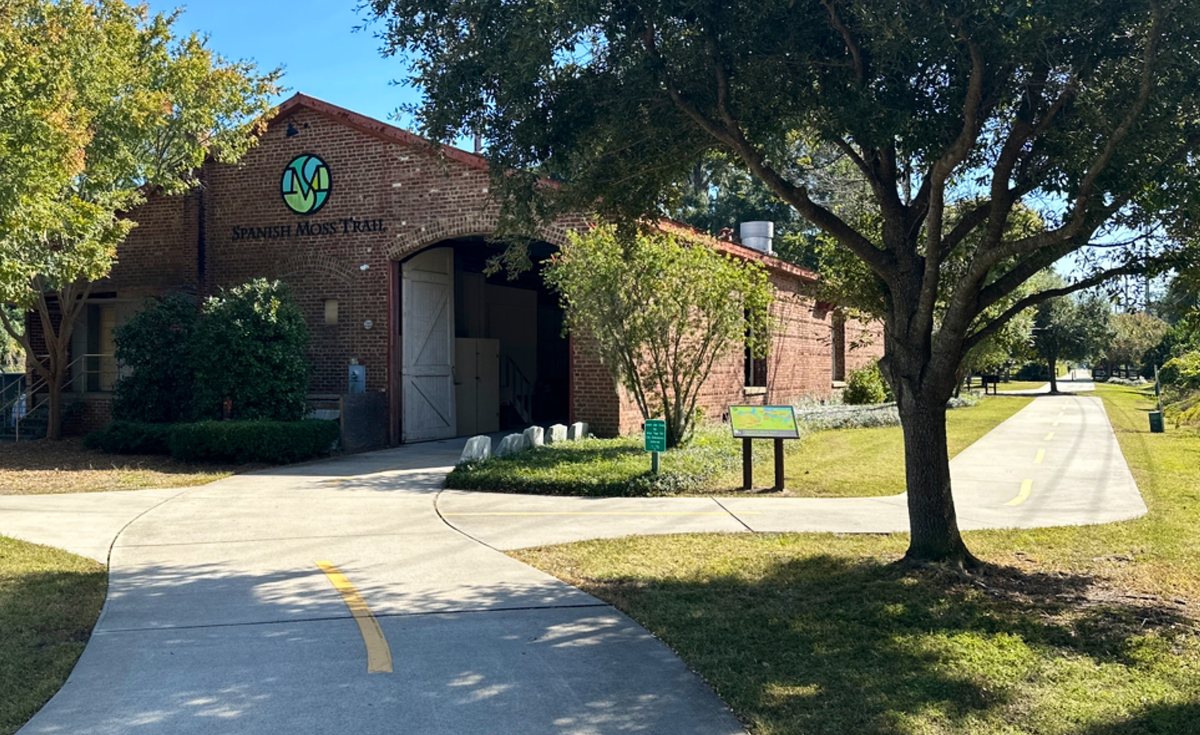 The old depot. The brick trailhead building in Beaufort, wearing the trail's green logo — the northern start of the Spanish Moss Trail.