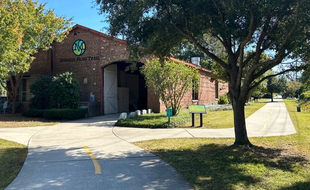 The old depot. The brick trailhead building in Beaufort, wearing the trail's green logo — the northern start of the Spanish Moss Trail.