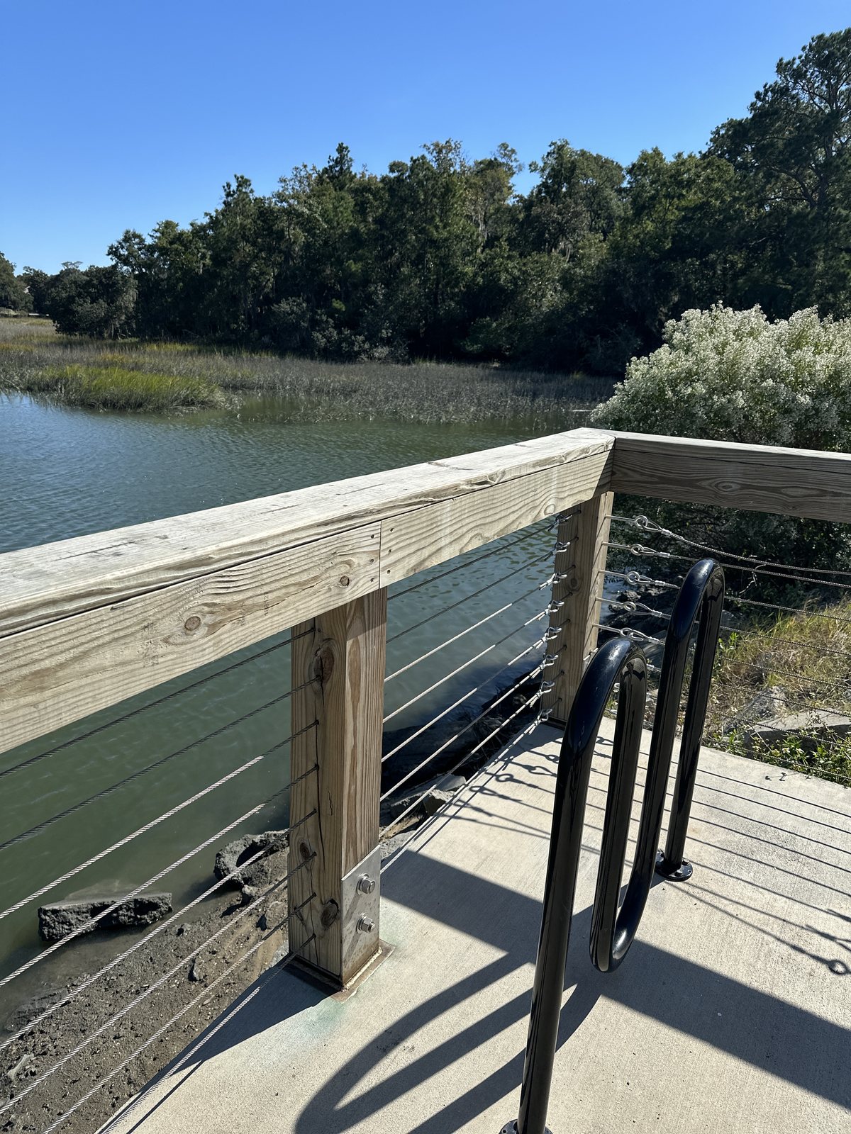 Over the creek. The fishing pier's rail above the marsh grass, the creek sliding under.