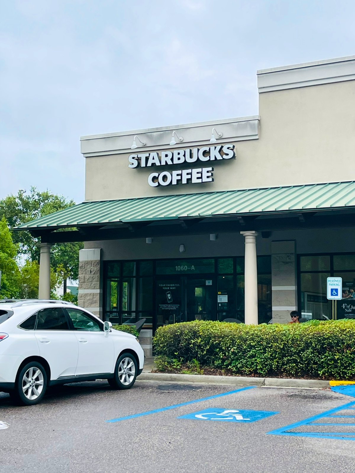 Starbucks Coffee in Bluffton — white letters over unit 1060-A, green metal roof and the reserved parking out front