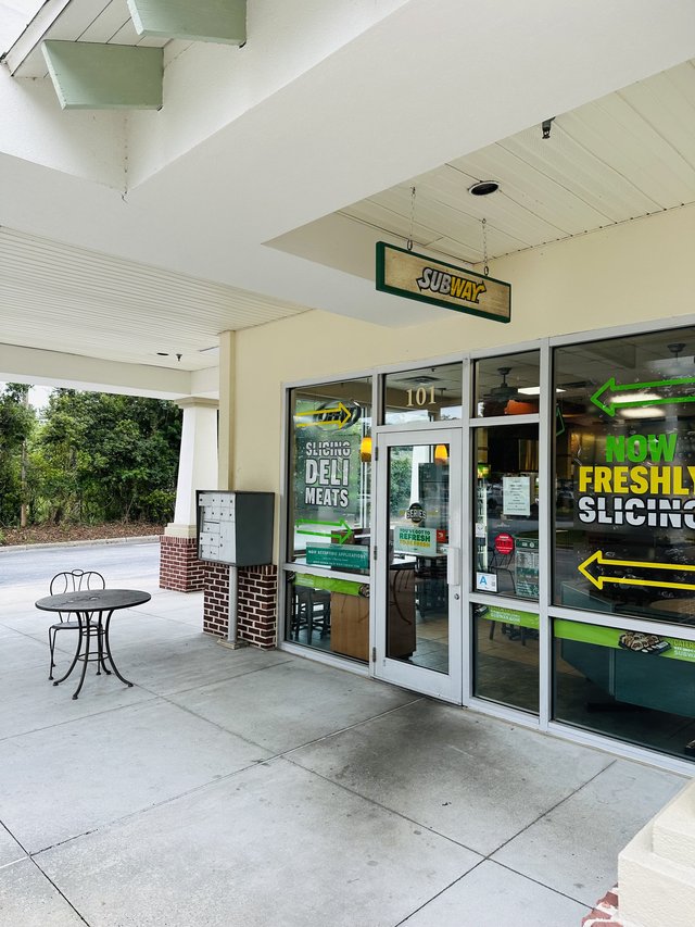 The Subway at Rose Hill in Bluffton — the hanging blade sign and unit 101 under the covered walkway, freshly-sliced decals on the glass