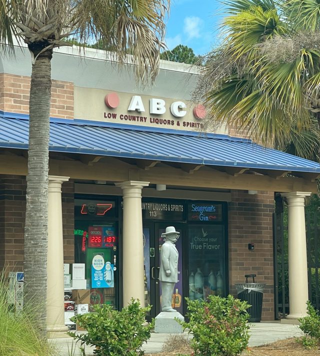 ABC Low Country Liquors near Tanger Outlets 1 — blue metal roof, palms, and a statue by the door