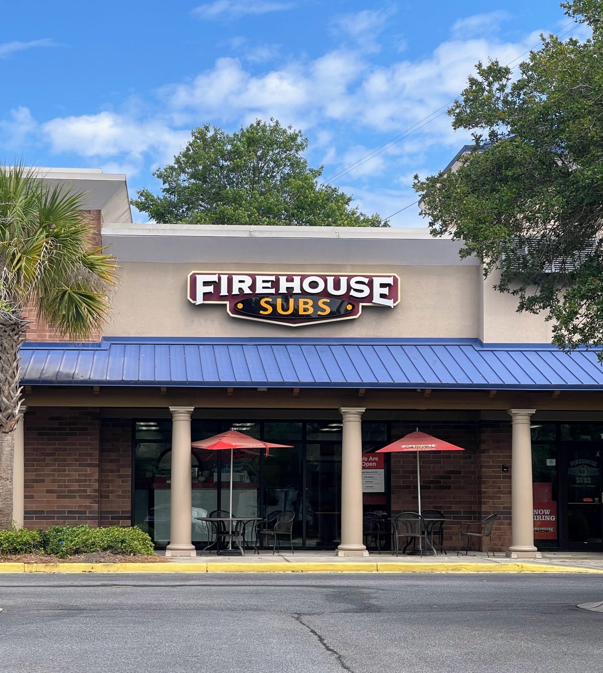 Firehouse Subs near Tanger Outlets 1 — big shield sign, blue metal roof, red patio umbrellas