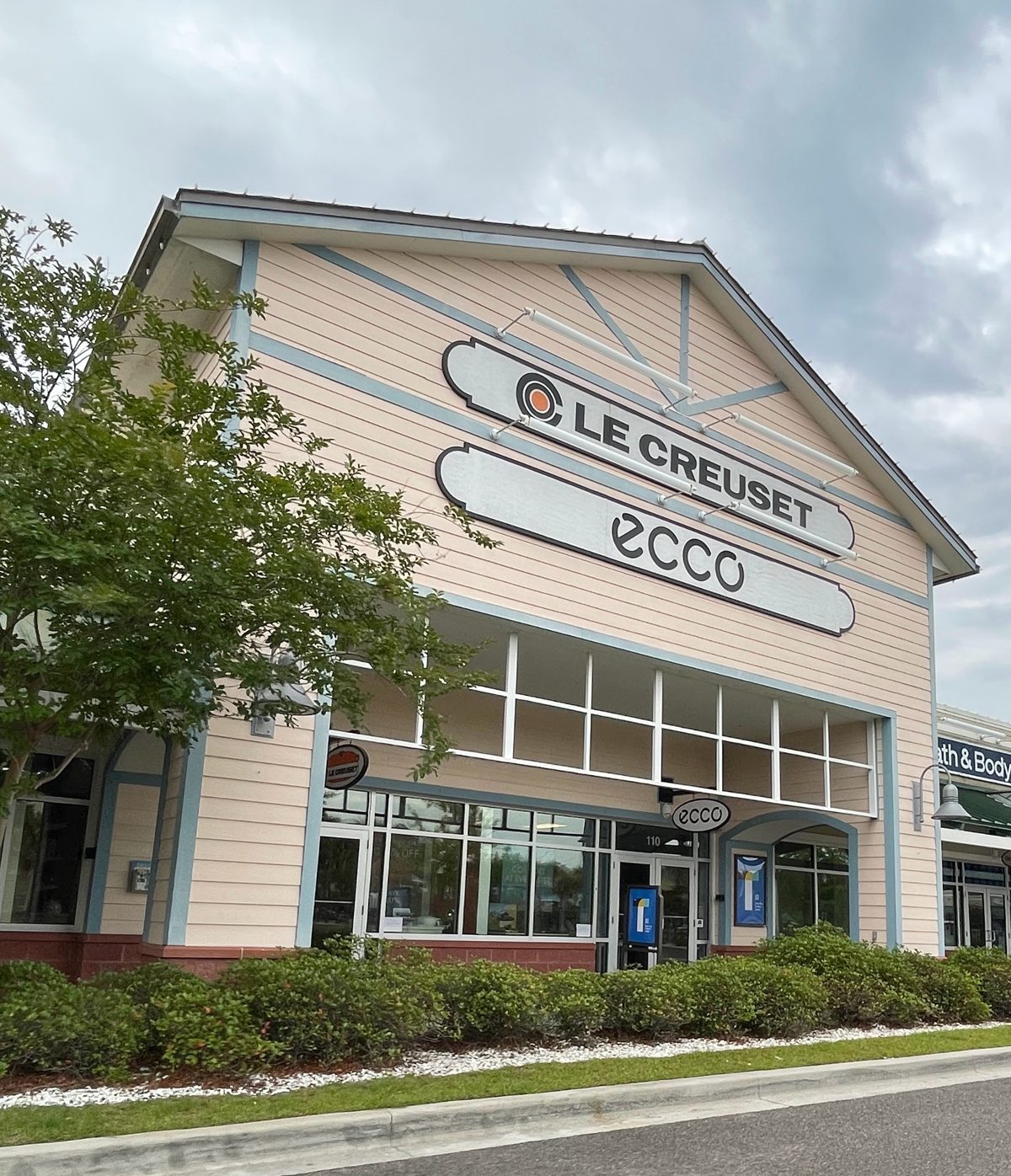 Le Creuset and ECCO signs on one tall storefront at Tanger Outlets 1