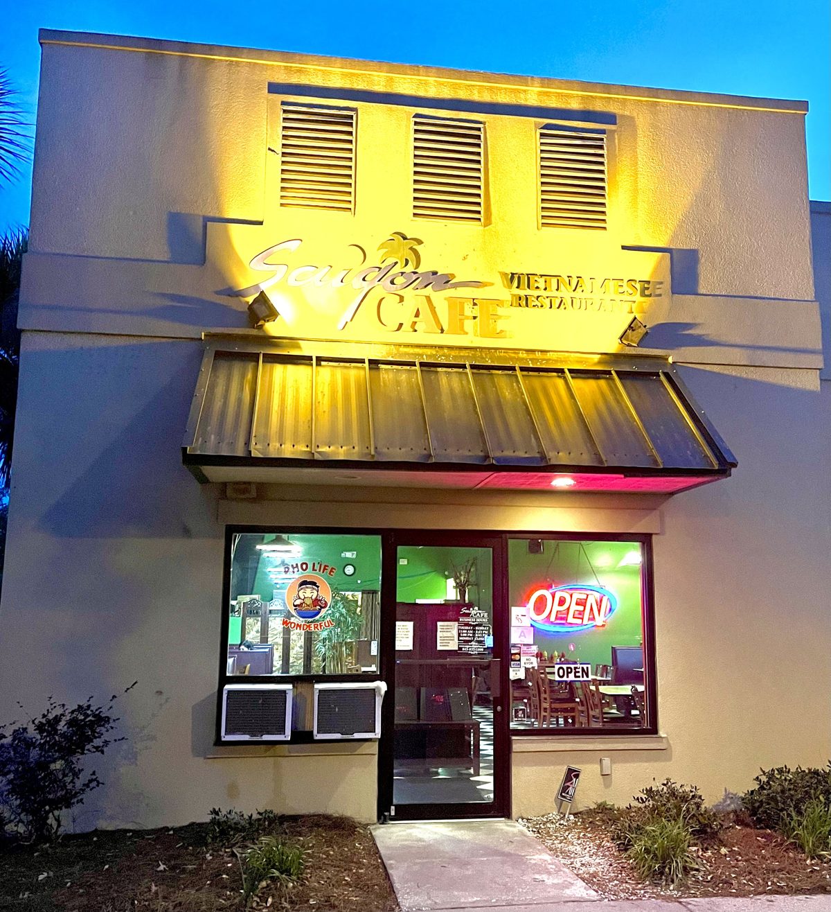 Saigon Café Vietnamese restaurant at dusk, gold sign lit and a neon OPEN sign in the window