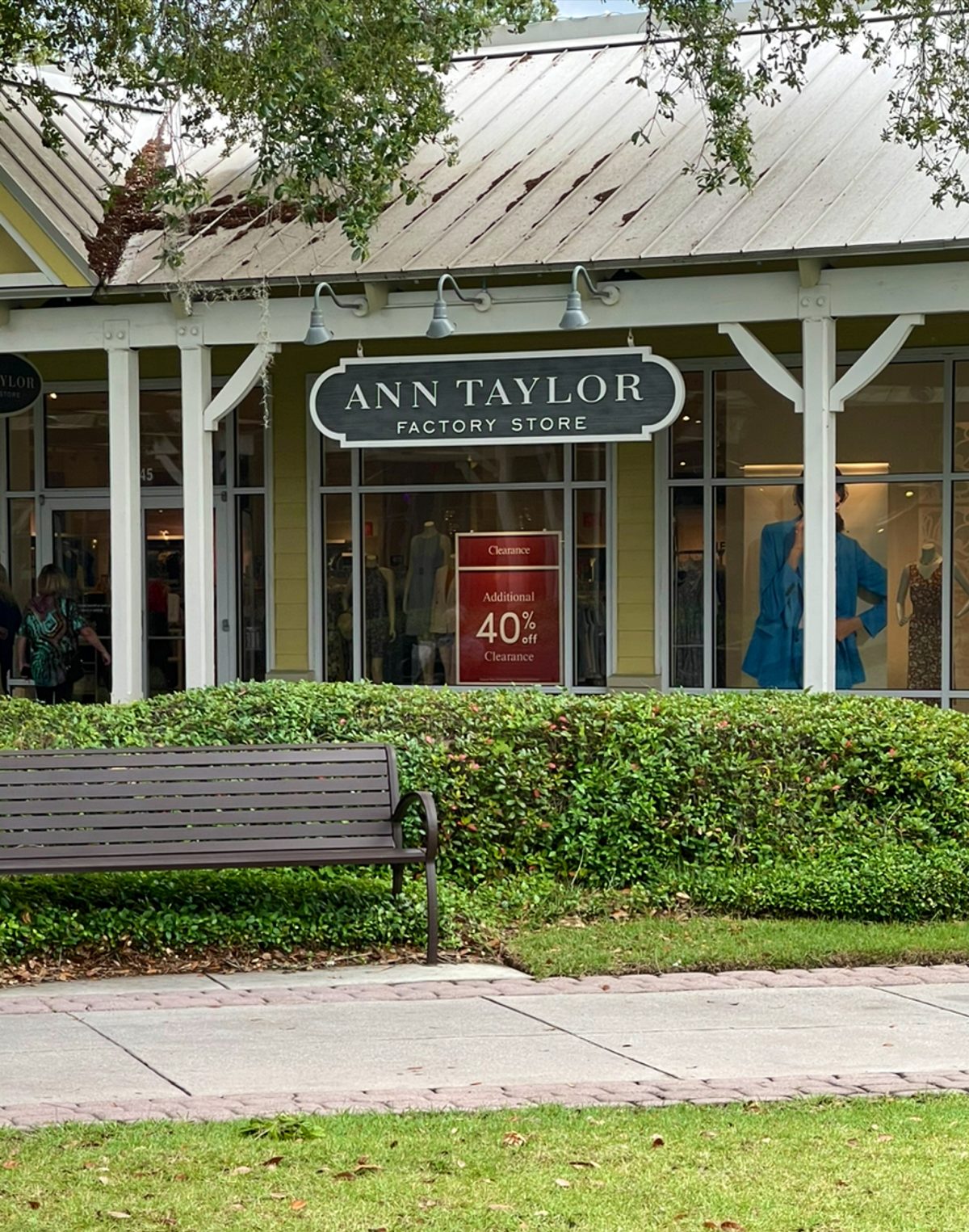 Ann Taylor Factory Store at Tanger Outlets 2 — black hanging sign, bench and hedge in front