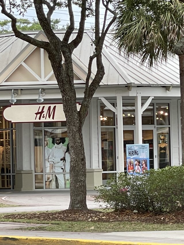 H&M at Tanger Outlets 2 — red letters on a white blade sign behind an oak tree