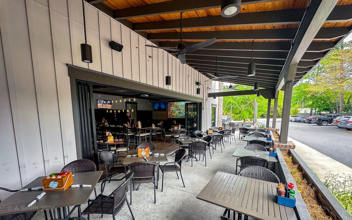 The covered patio at The Smokehouse — open-air tables under the roof, looking into the dining room
