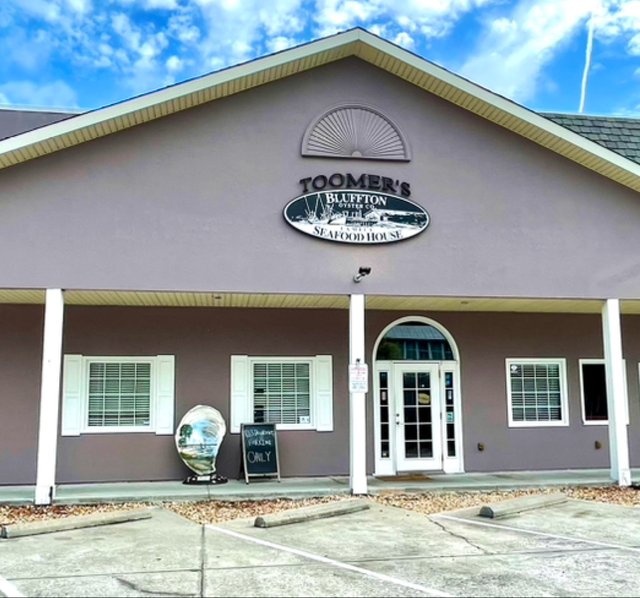 Toomer's Bluffton Oyster Co. Seafood House in Bluffton — the oval sign on the mauve building and a giant oyster shell by the porch