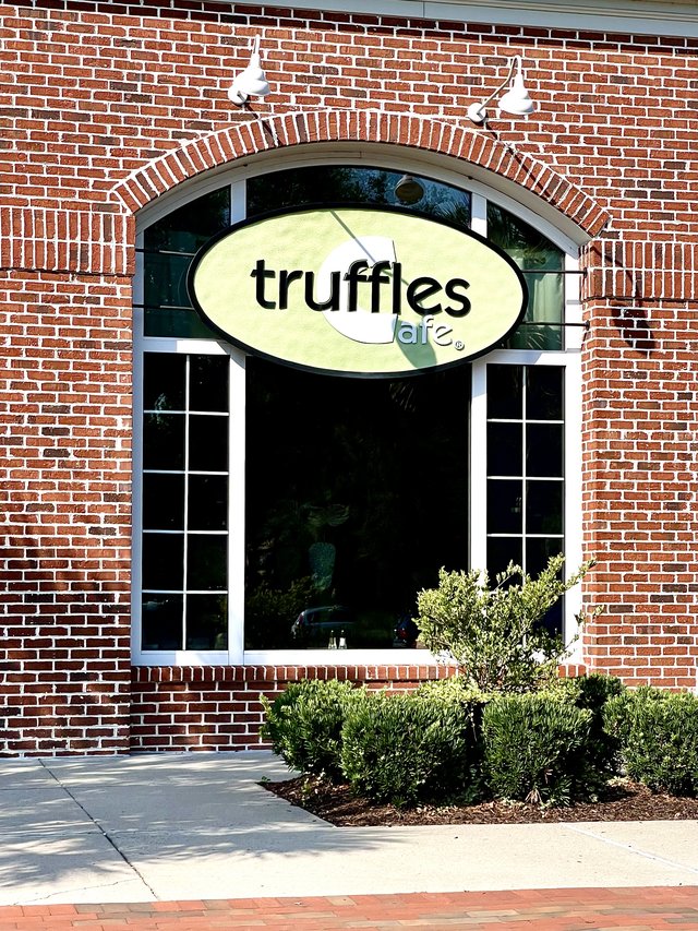Truffles Cafe green oval sign hung in a red-brick arched window, Belfair Plaza, Bluffton SC