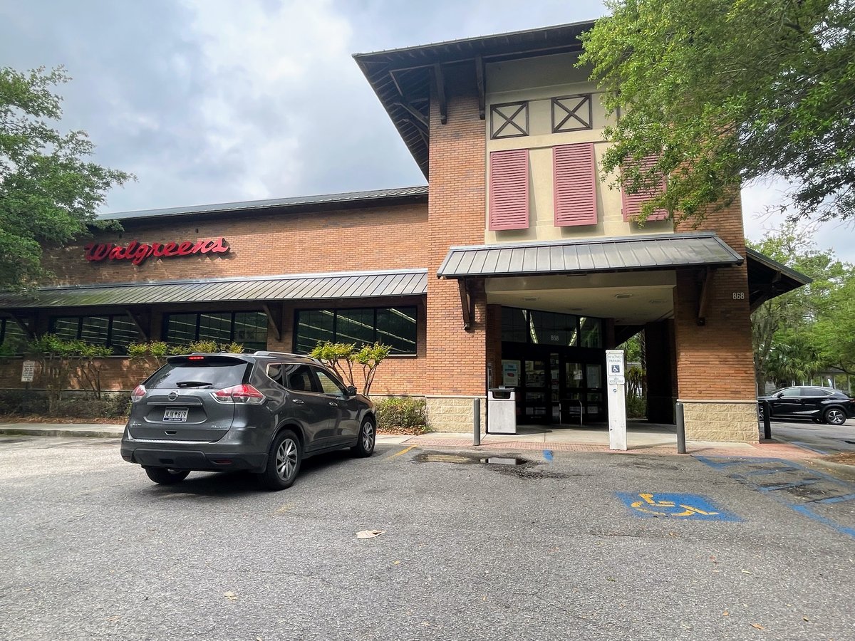 The Bluffton Walgreens — red script sign on brick, pink shutters and a deep porch roof over the entrance