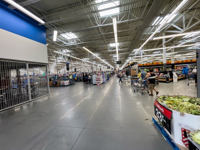 Inside the Bluffton Walmart — the long main aisle, produce on the right, checkouts on the left, corn on rollback in front