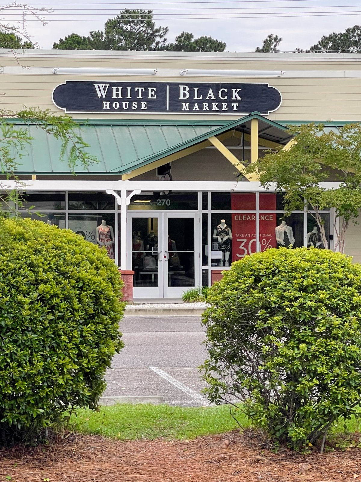 White House Black Market at Tanger Outlets 1 in Bluffton — the black plaque sign, green roof, mannequins and a clearance banner in the windows